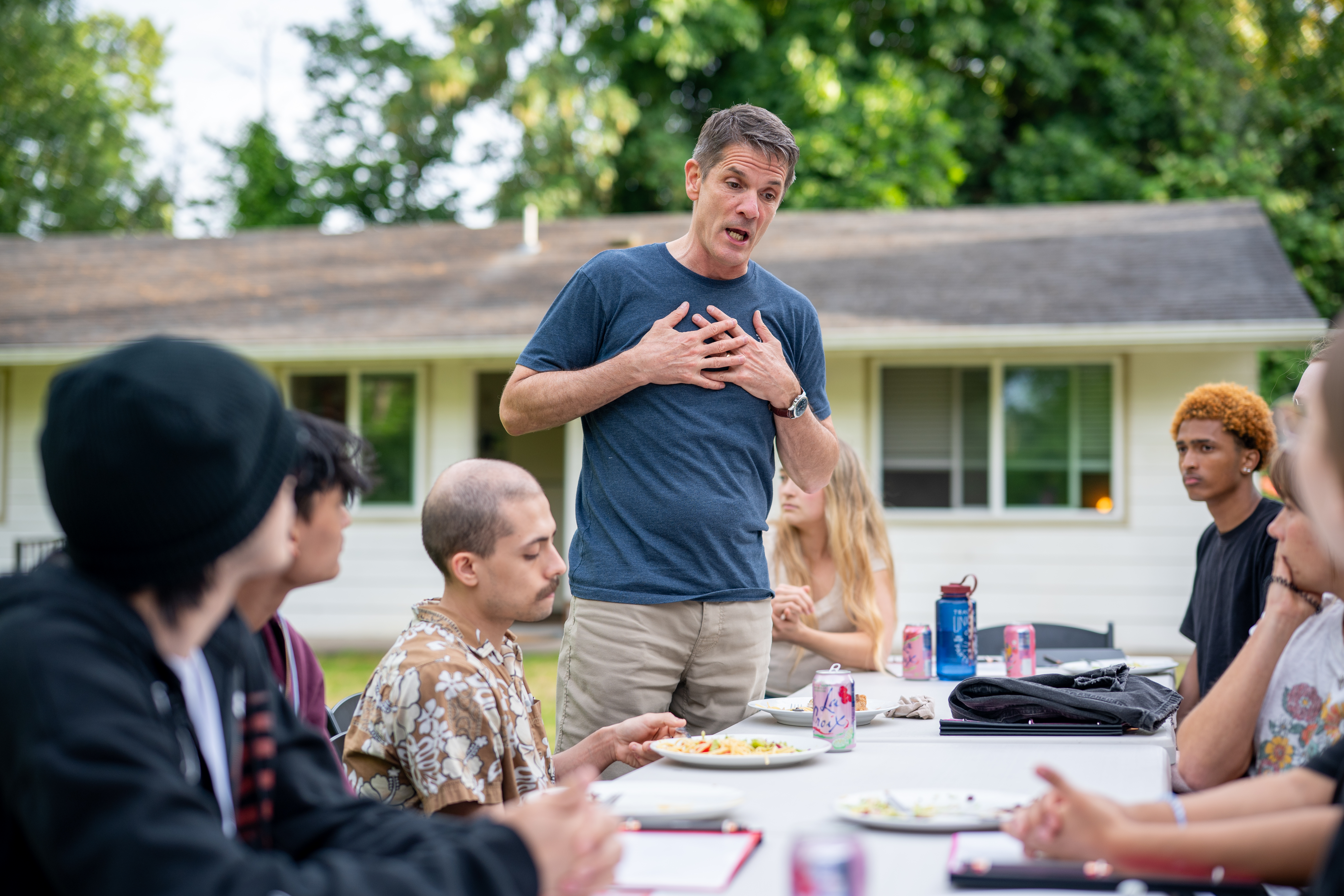 A mentor speaking earnestly with young people during an outdoor gathering