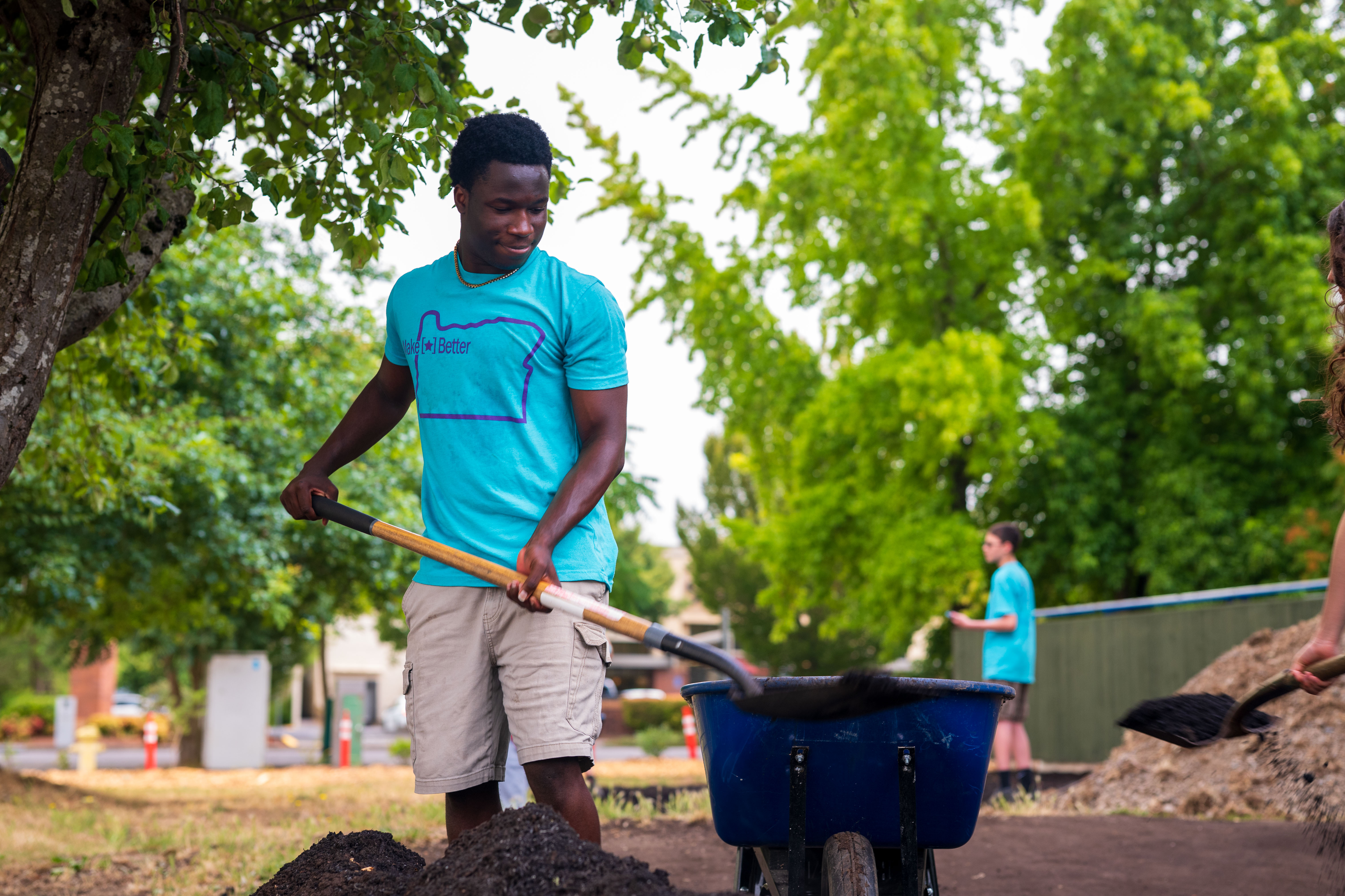 A CAREcorps participant moving soil with a wheelbarrow